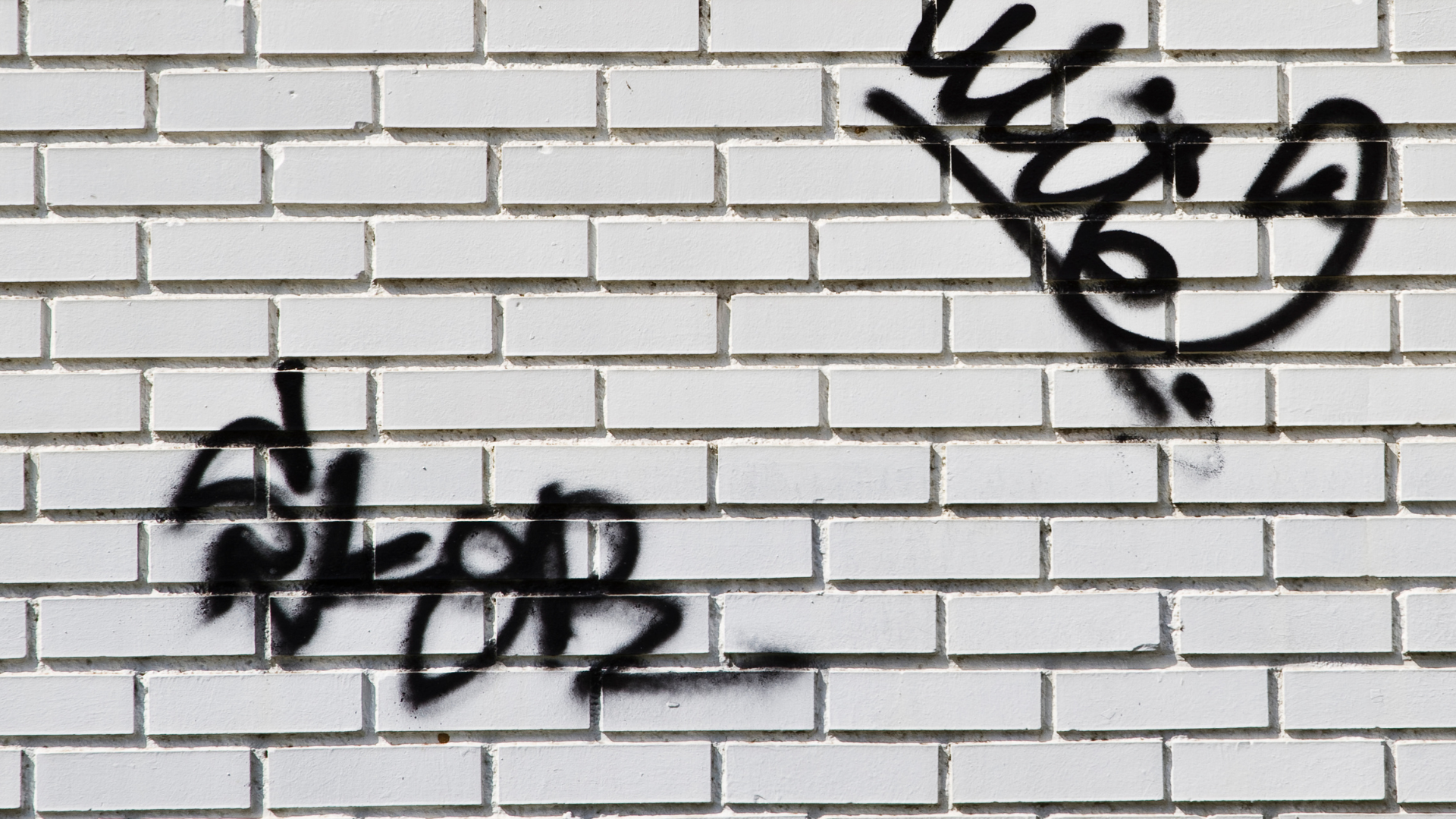 Graffiti tags on a white brick wall
