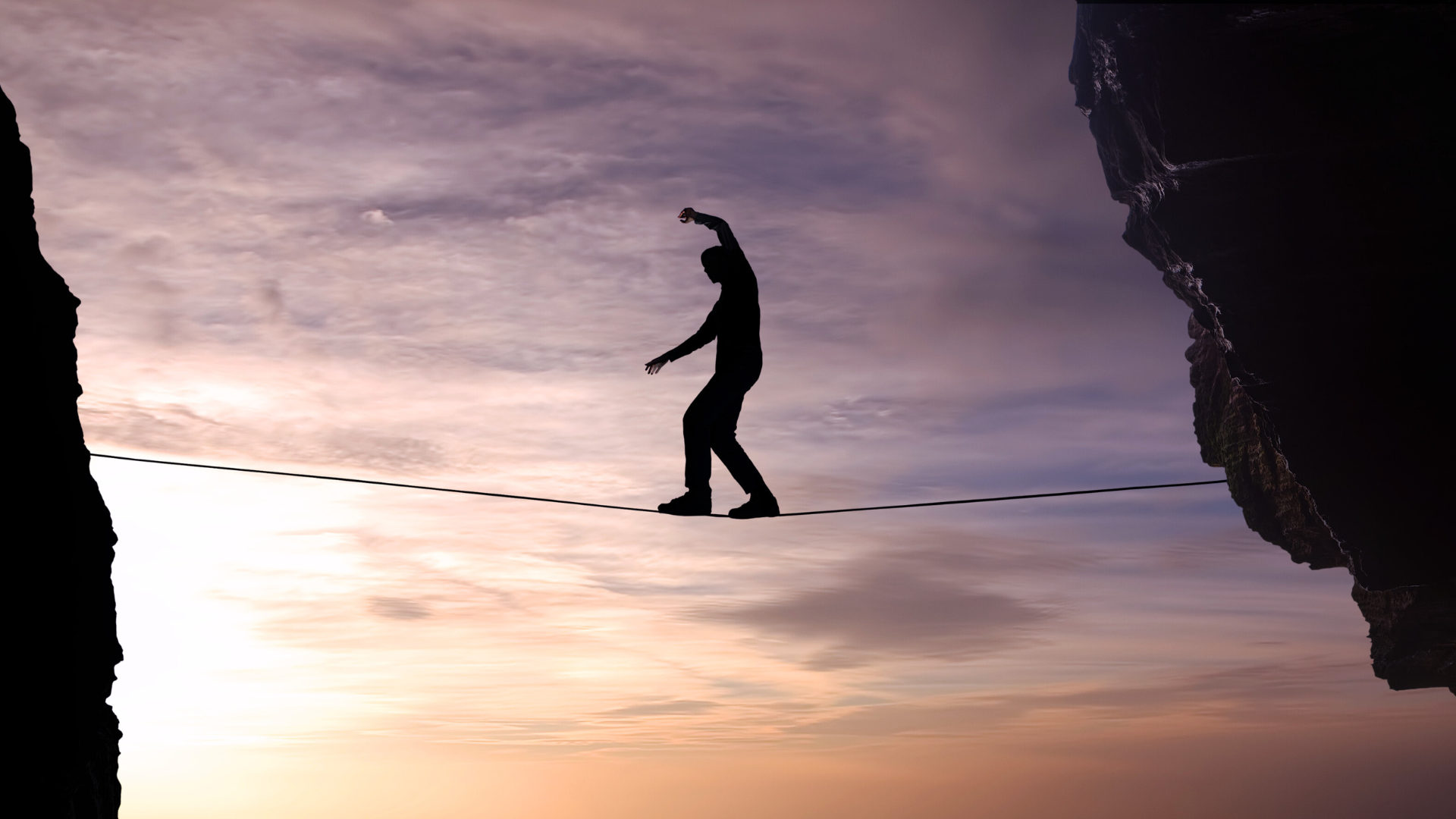 Person walking on a tightrope between two cliff-faces