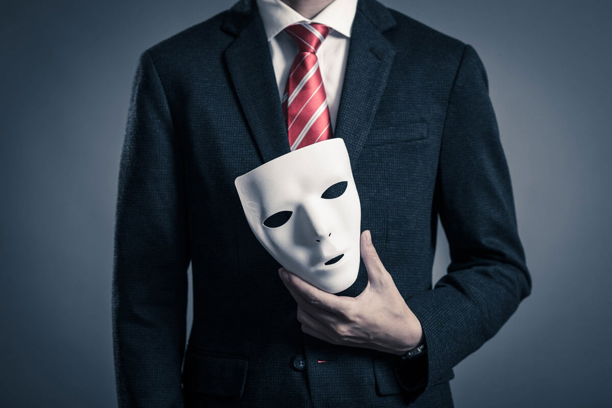 Man wearing a suit and holding a white face mask