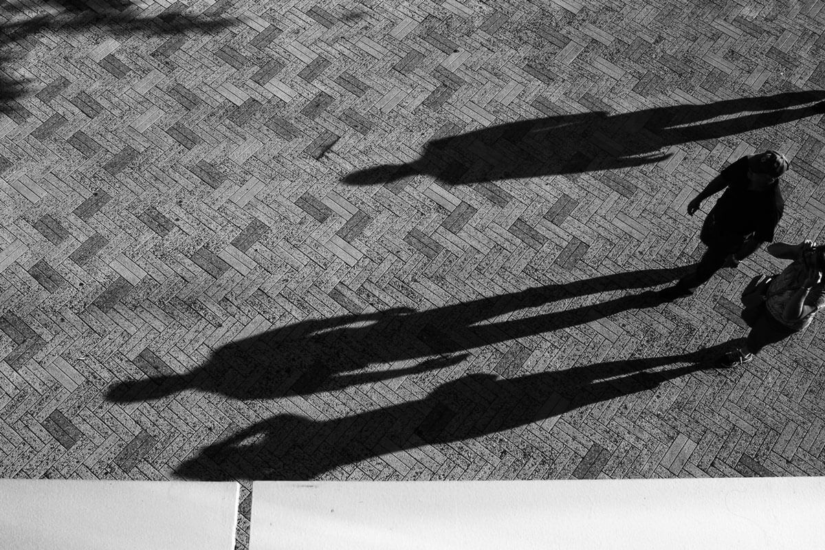 Many people's shadow casting onto a brick road